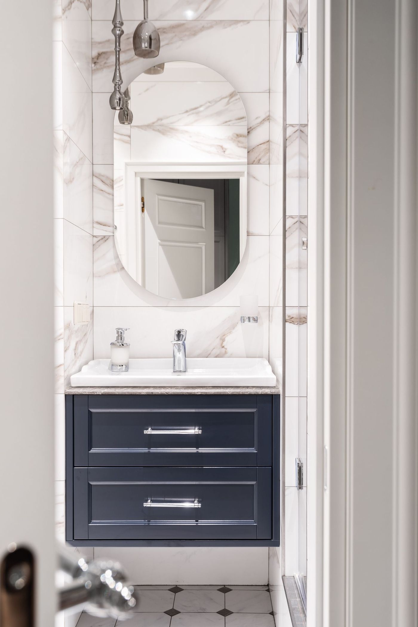 Spotless marble bathroom with a navy vanity and round mirror