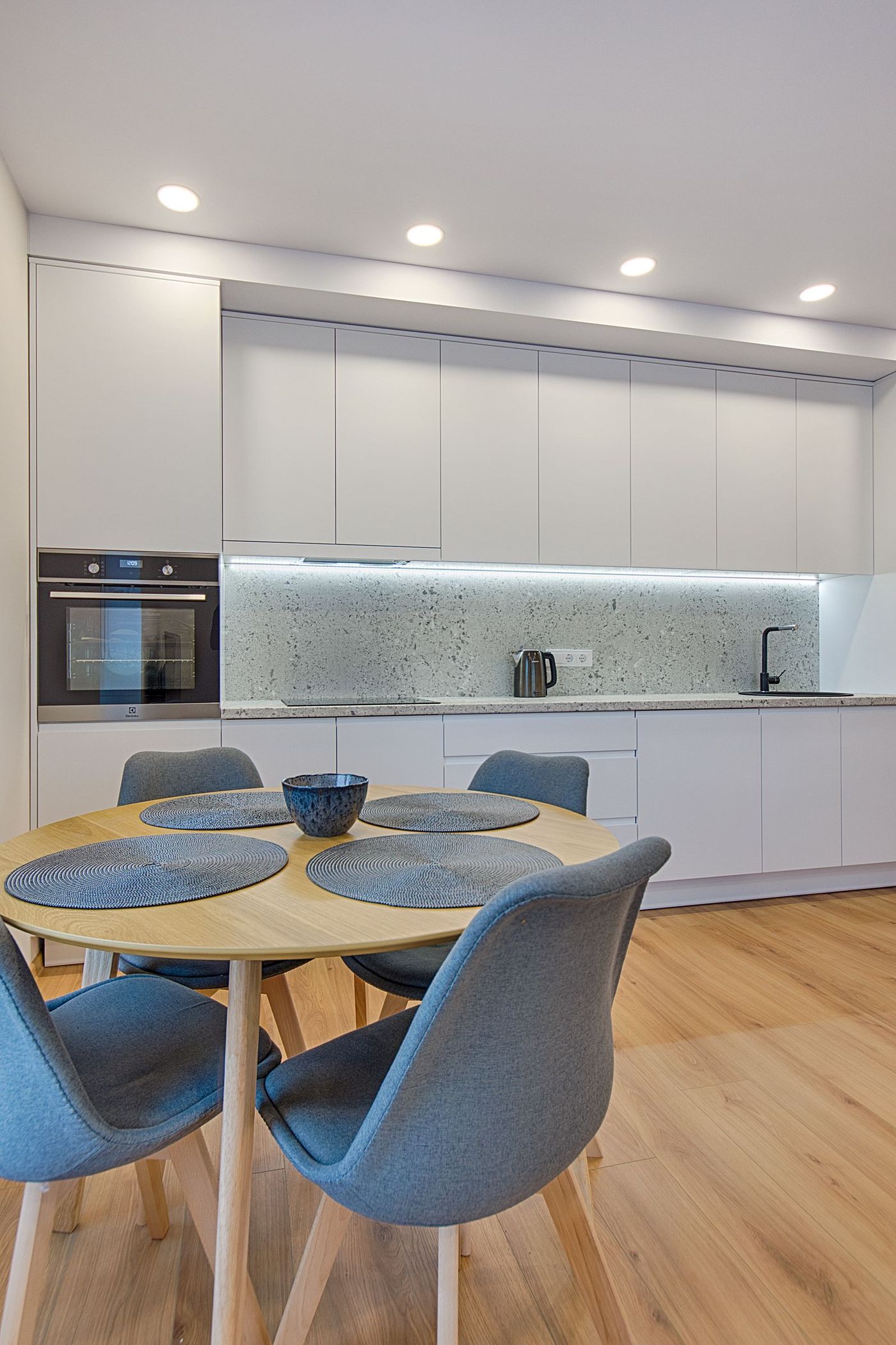 Bright white kitchen and dining area with blue chairs after cleaning