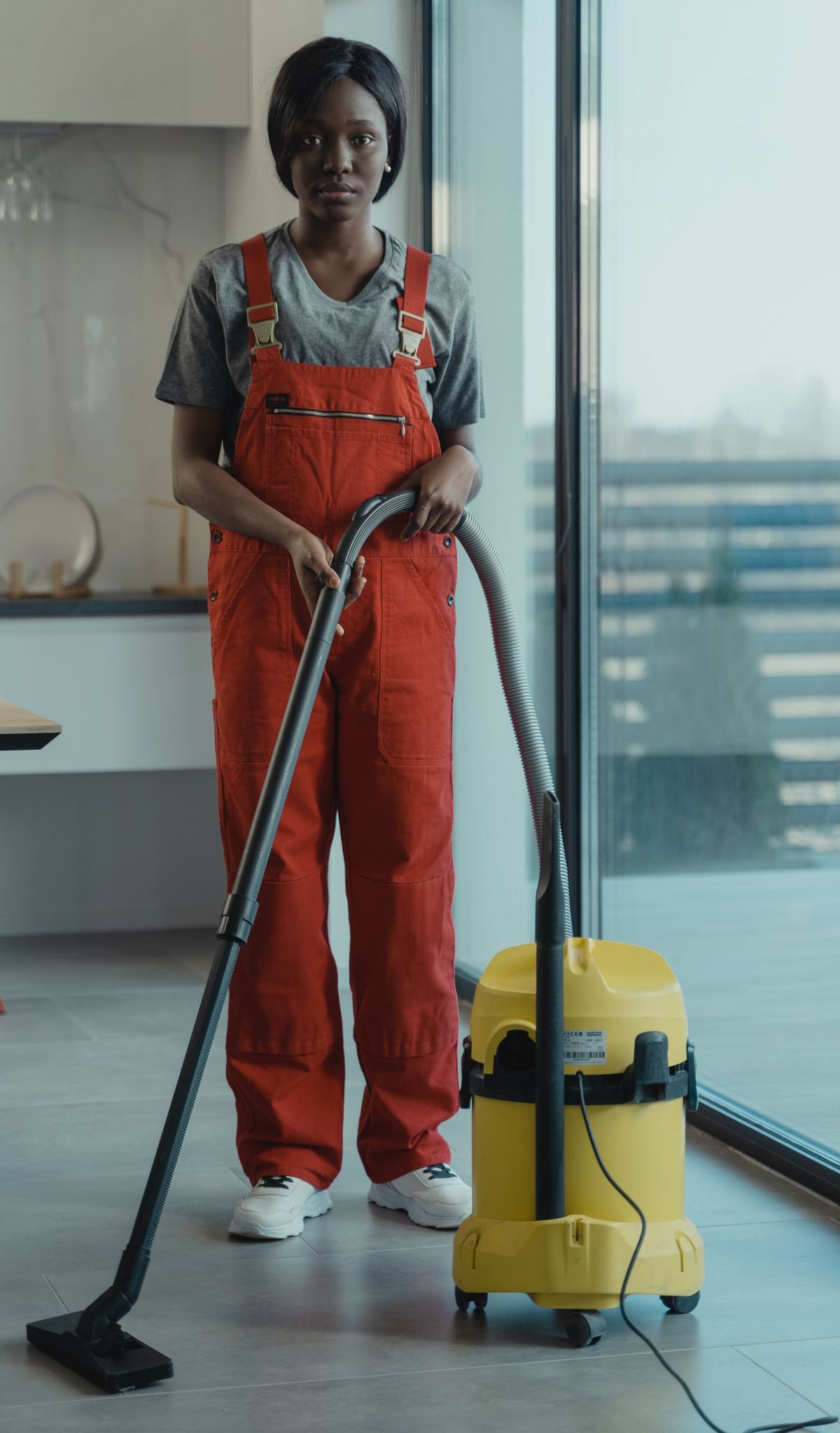 A professional cleaner with a vacuum in a bright, modern home
